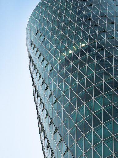 Modernes Hochhaus mit einer gläsernen Fassade und dreieckigem Muster.